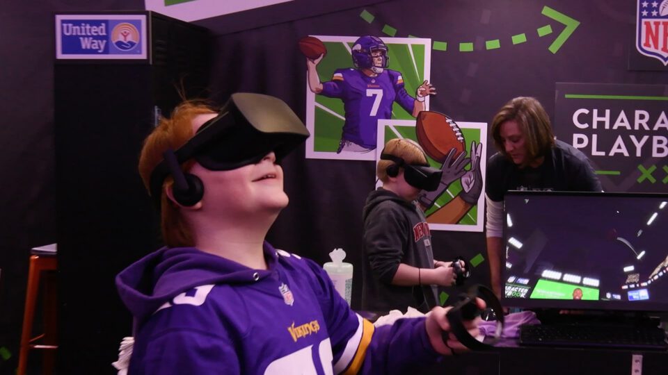 Kids play NFL VR game with headset, purple jerseys, and interactive booth