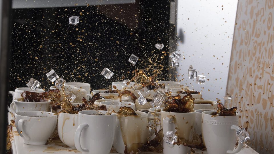 Coffee splashing from mugs with ice cubes flying mid-air