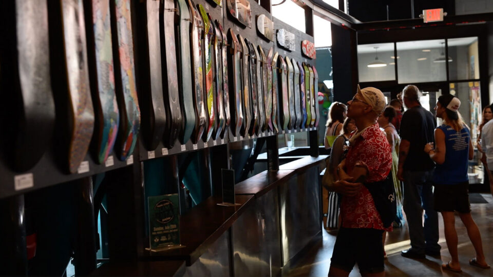 People browse displayed skateboards in a well-lit indoor space.