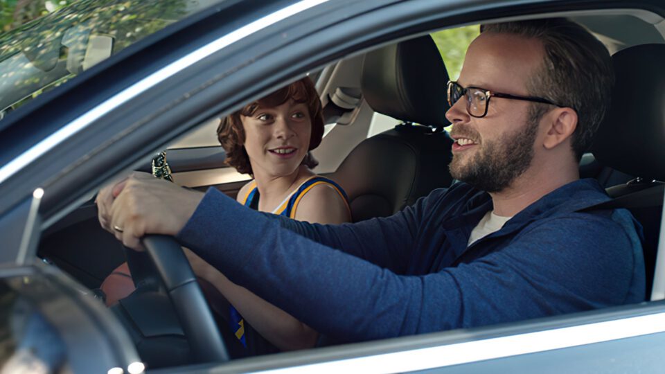 Man and boy smiling while driving a car together.