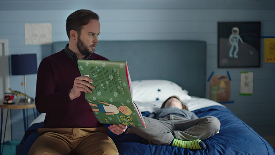 Man reading bedtime story to child in bedroom