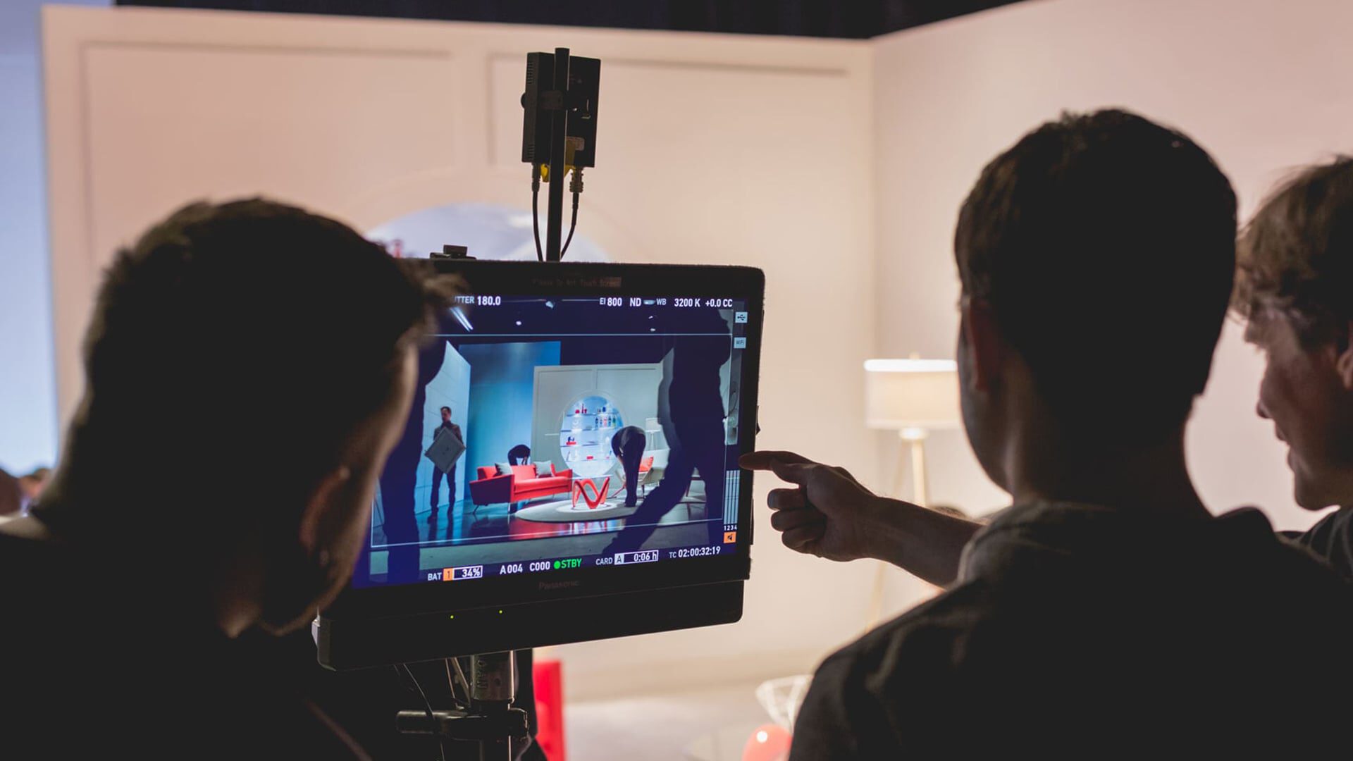 Film crew reviews shot on monitor showing staged scene with figures and robot.