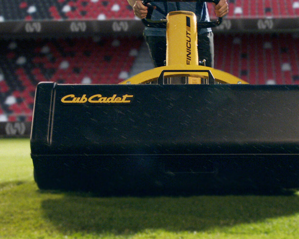 Person operating yellow Cub Cadet Fincut mower on green turf field