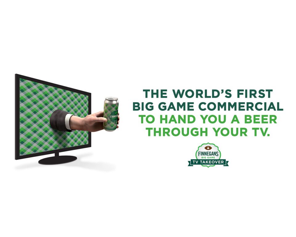 A hand extends from a TV screen, holding a green FinneGans beer can.