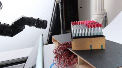 Professional camera setup capturing rows of red lipstick products in studio