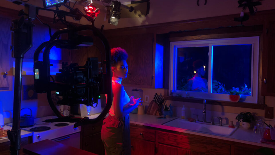 Person filming in a dimly lit kitchen with blue and red lighting.