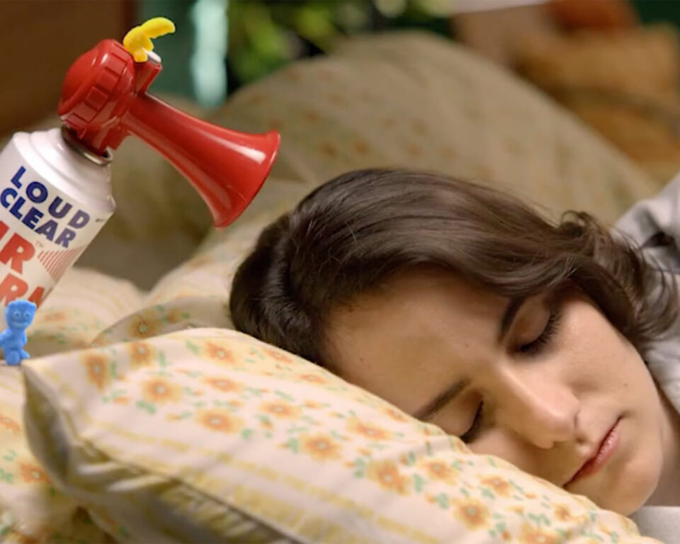 Sleeping person with a "LOUD CLEAR" air horn nearby