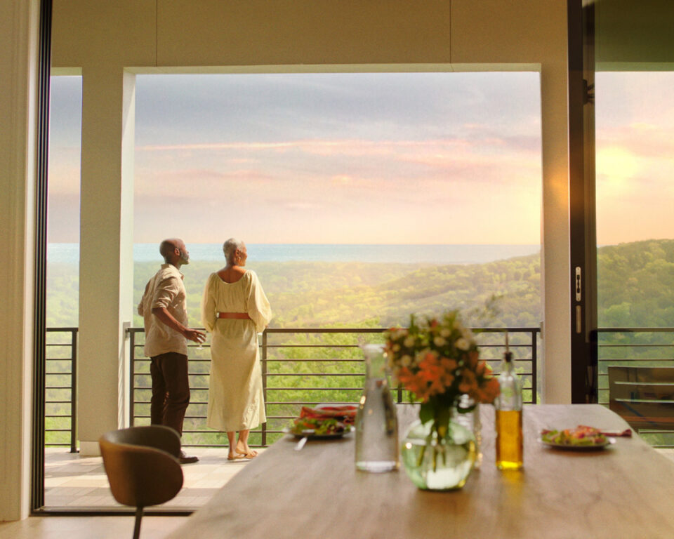 Elderly couple enjoys scenic view from modern balcony at sunset.