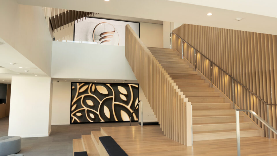 Modern wooden staircase with handrails, featuring abstract art on walls.