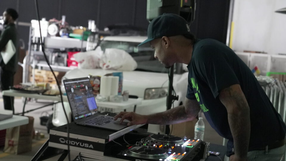 DJ operating laptop and turntables at a music event setup