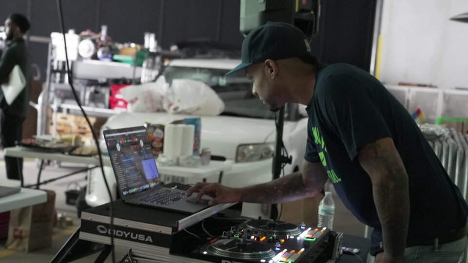 DJ operating laptop and turntables at a music event setup