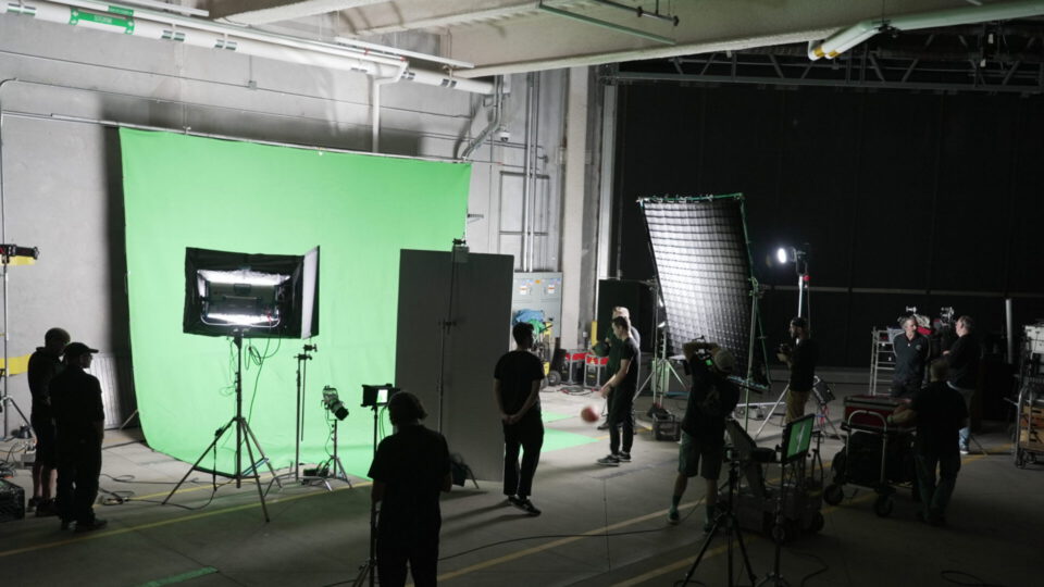 Film crew working on green screen set with lighting and cameras