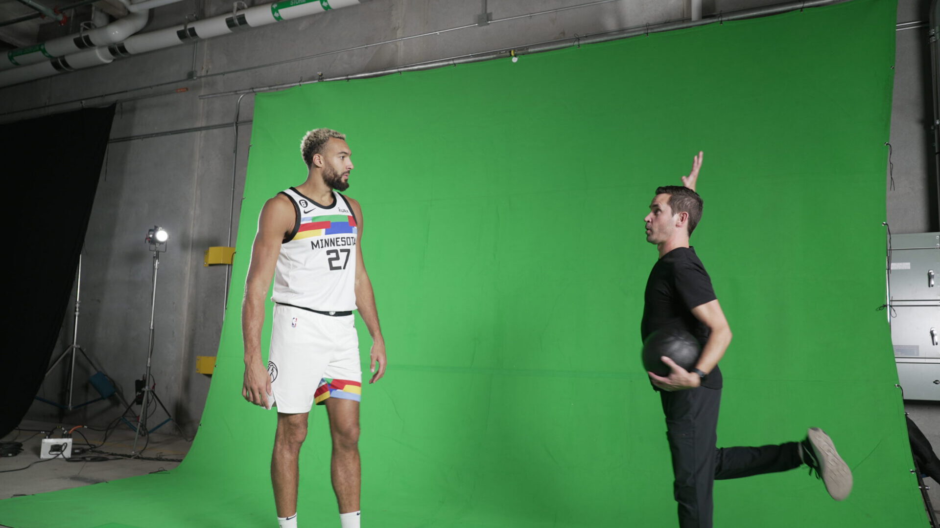 NBA player in Minnesota jersey poses with coach on green screen set