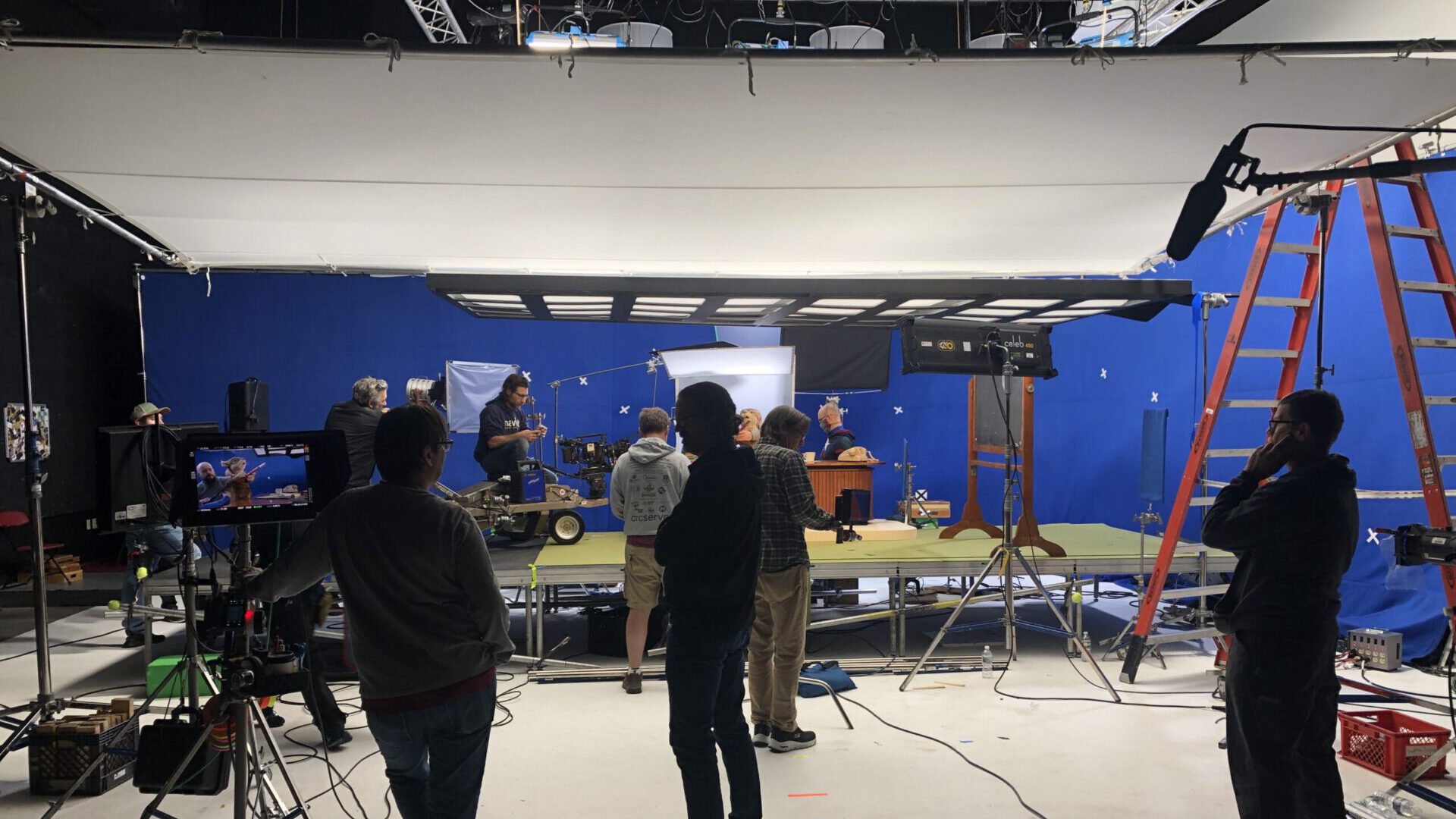 Film crew working on set with blue screen and lighting equipment