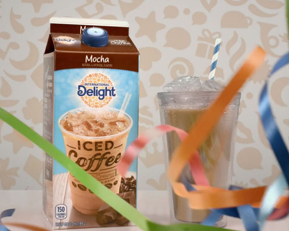 Mocha-flavored iced coffee carton next to a glass with a straw and festive ribbons.