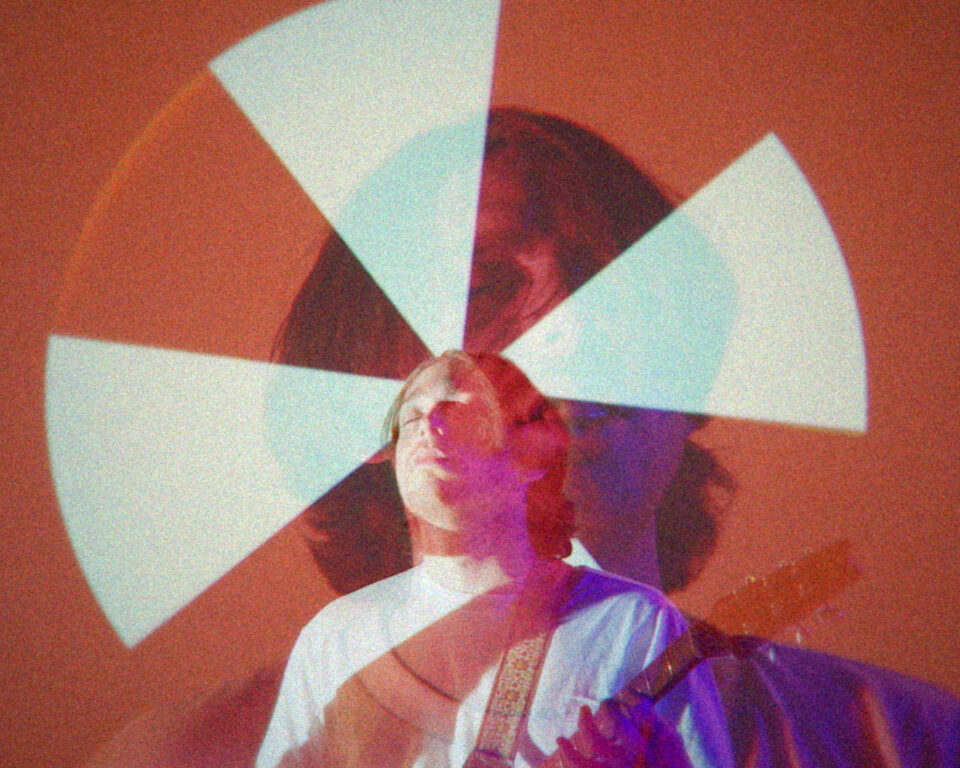 Person playing guitar with colorful light patterns overlaying their face