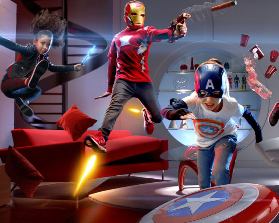Three children in superhero costumes playfully battle in a modern living room.