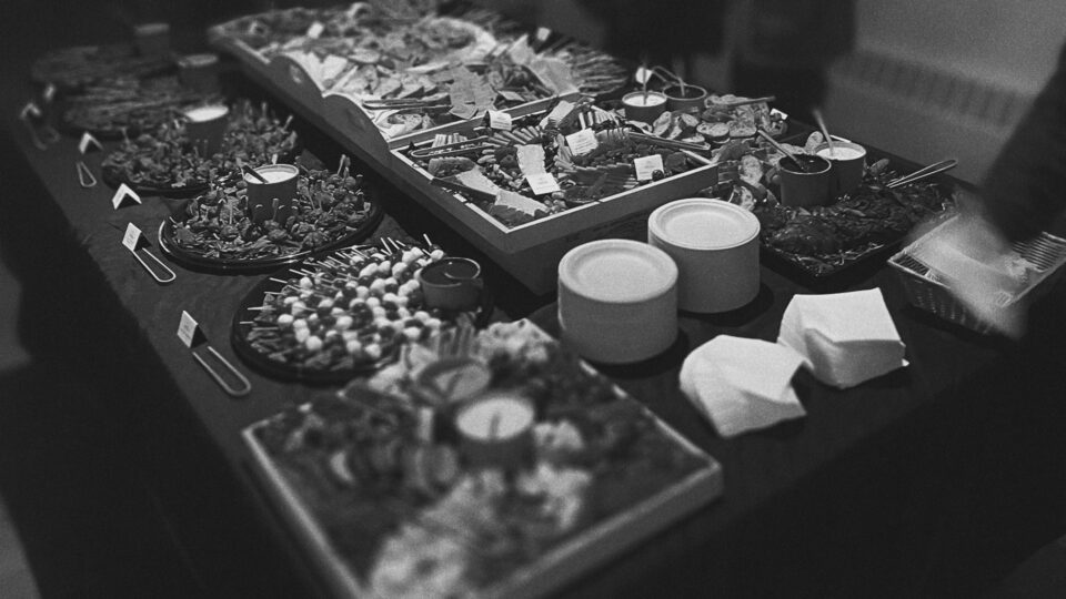 Black-and-white buffet table with assorted snacks, candles, and serving utensils.