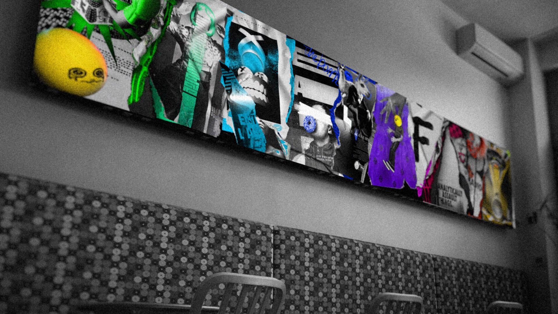 Vibrant collage art with green, blue, and purple accents on a monochrome wall above patterned seating.