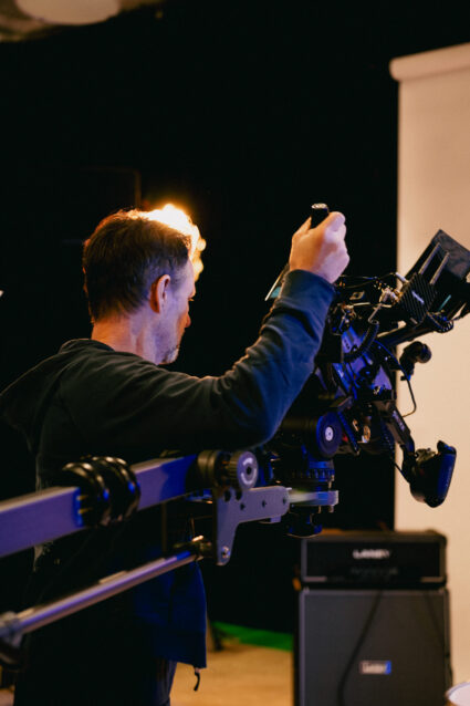 Film crew member operating professional camera on set