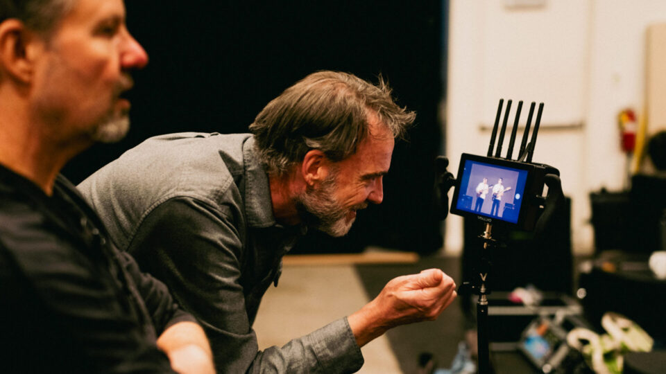 Director reviews live stage performance on camera monitor with crew.