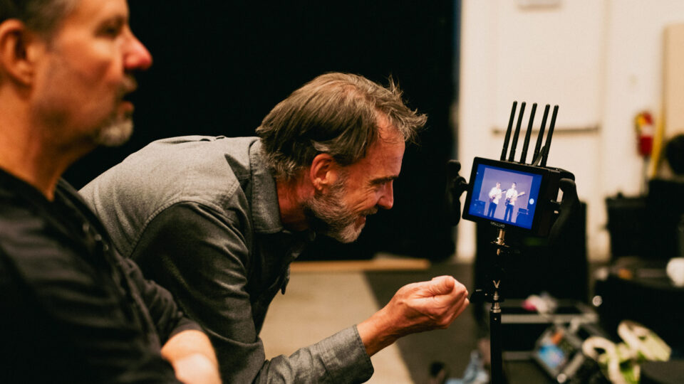 Director reviews live stage performance on camera monitor with crew.
