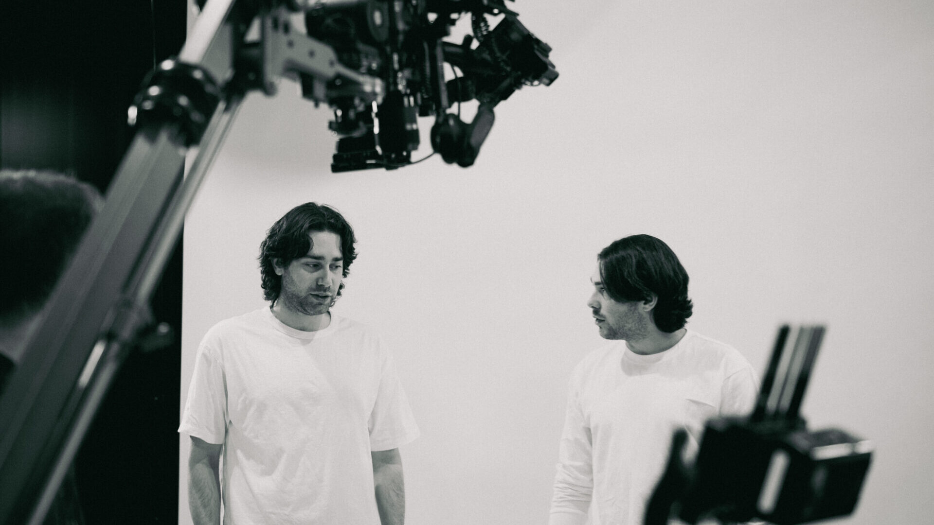 Two men in white shirts on film set with cameras and equipment