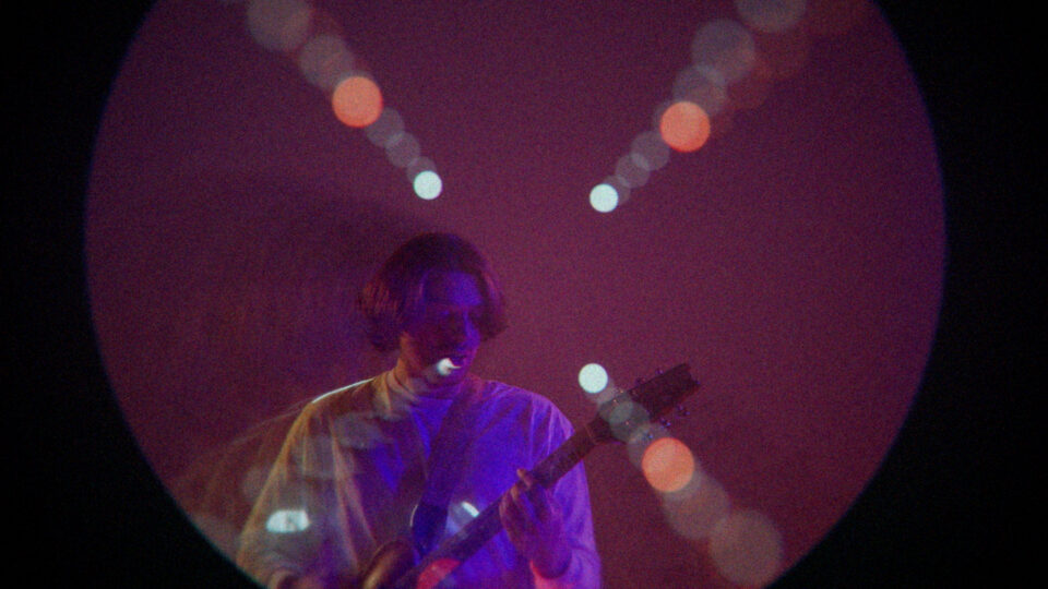 Musicialian playing guitar under purple stage lights with bokeh effect