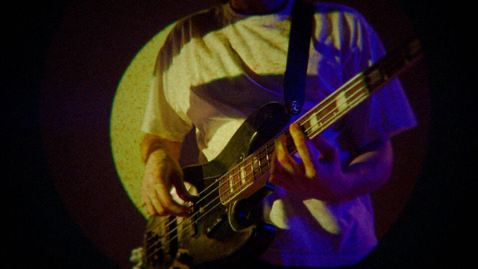 Person playing bass guitar under colorful stage lights