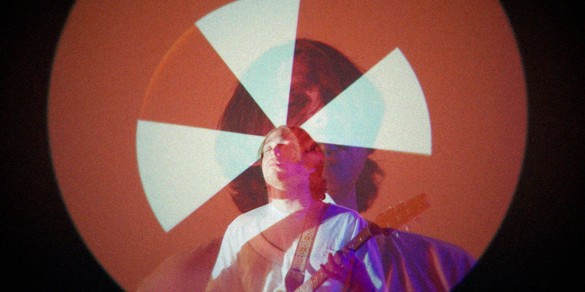 Person playing guitar under colorful circular light projection