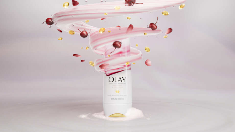 Olay body cream swirl with cherries and golden droplets floating around bottle