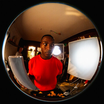 Man in red shirt photographed with fisheye lens in studio setting
