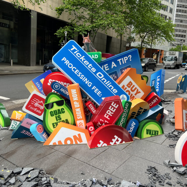 Colorful, chaotic pile of digital marketing signs on a city sidewalk
