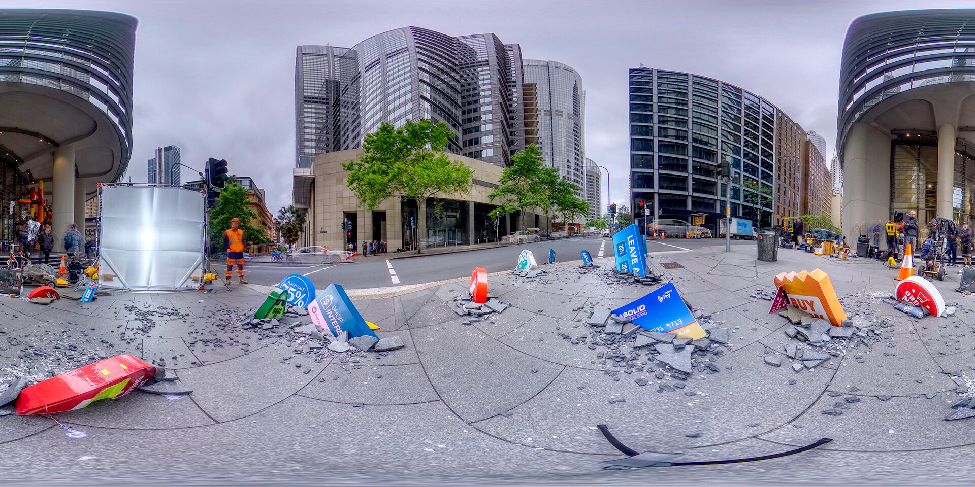 City street scene with scattered debris, broken signs, and modern buildings in background.